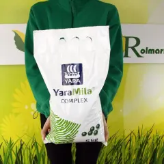 Osoba w zielonej bluzie trzyma biały worek nawozu YaraMila COMPLEX 5kg.